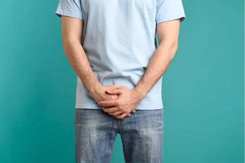Mann hält beide Hände vor die Blase - Prostatabeschwerden